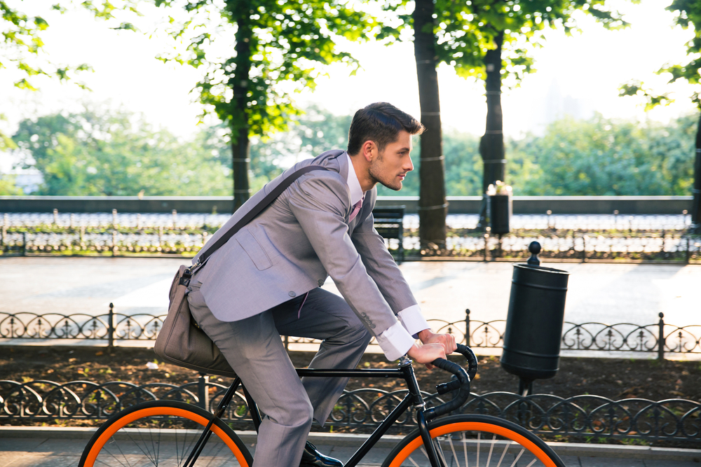 Businessman riding bicycle to work in city park